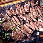 Traditional barbecue skirt steak sliced as close-up on a wooden board