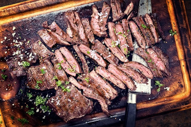 Traditional barbecue skirt steak sliced as close-up on a wooden board