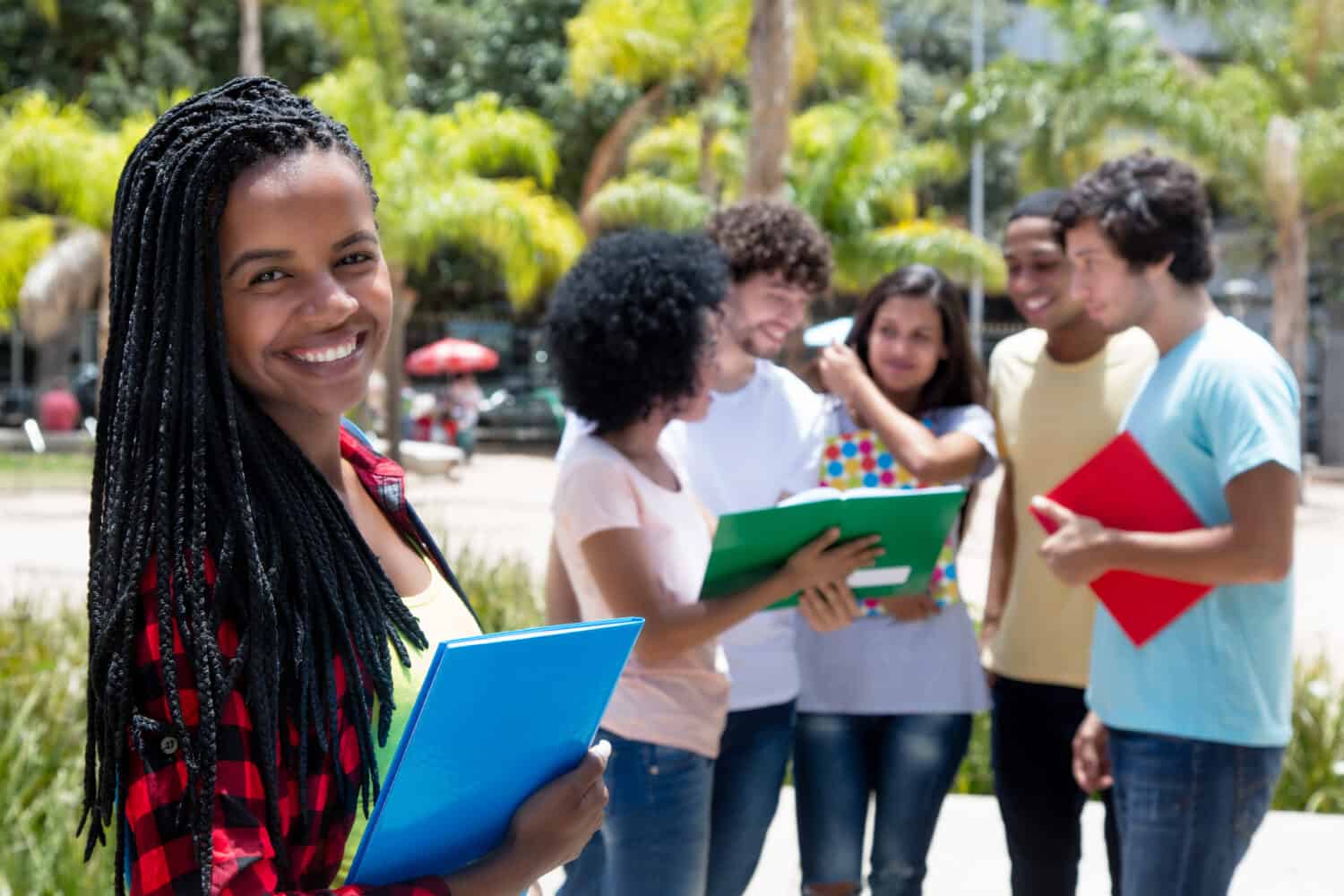 Laughing african female student with group of students outdoor on campus of university in summer