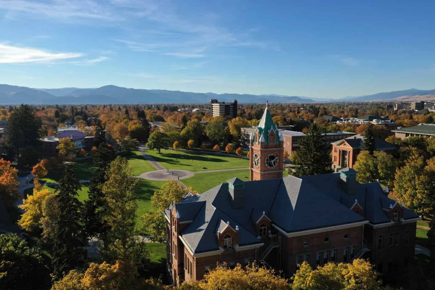 Looking northeast over the Main Hall clock tower and The Oval at the University of Montana during Autumn, with the Missoula Valley stretching out into the distance.