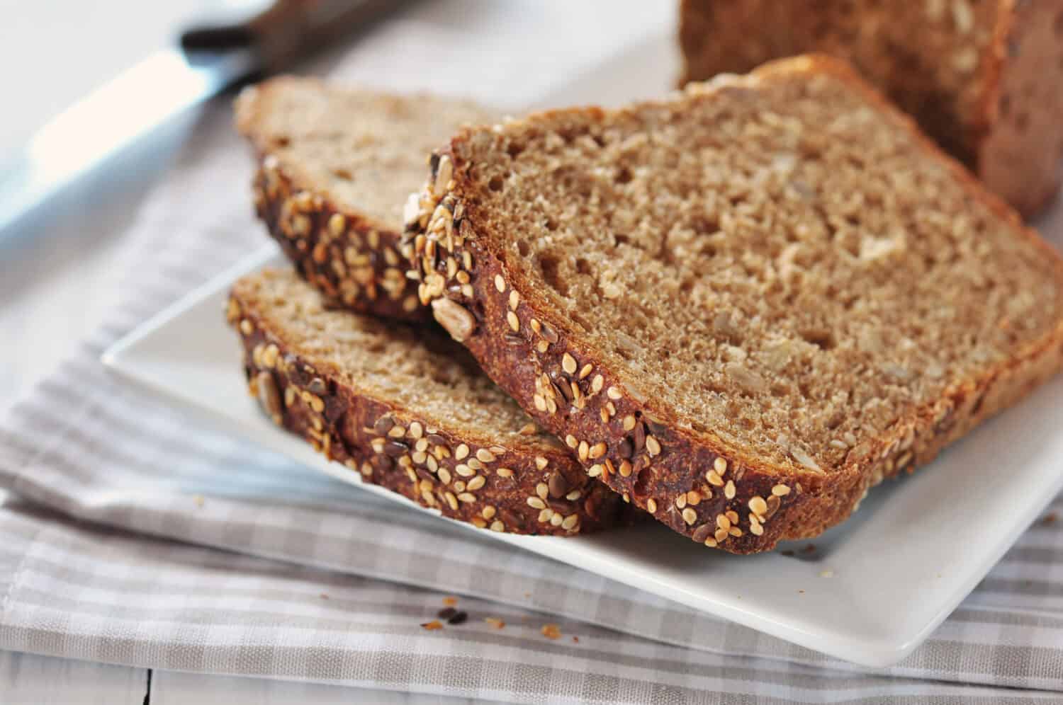 White bread vs. wheat bread: Sliced wheat bread with sunflower seeds and sesame on a plate