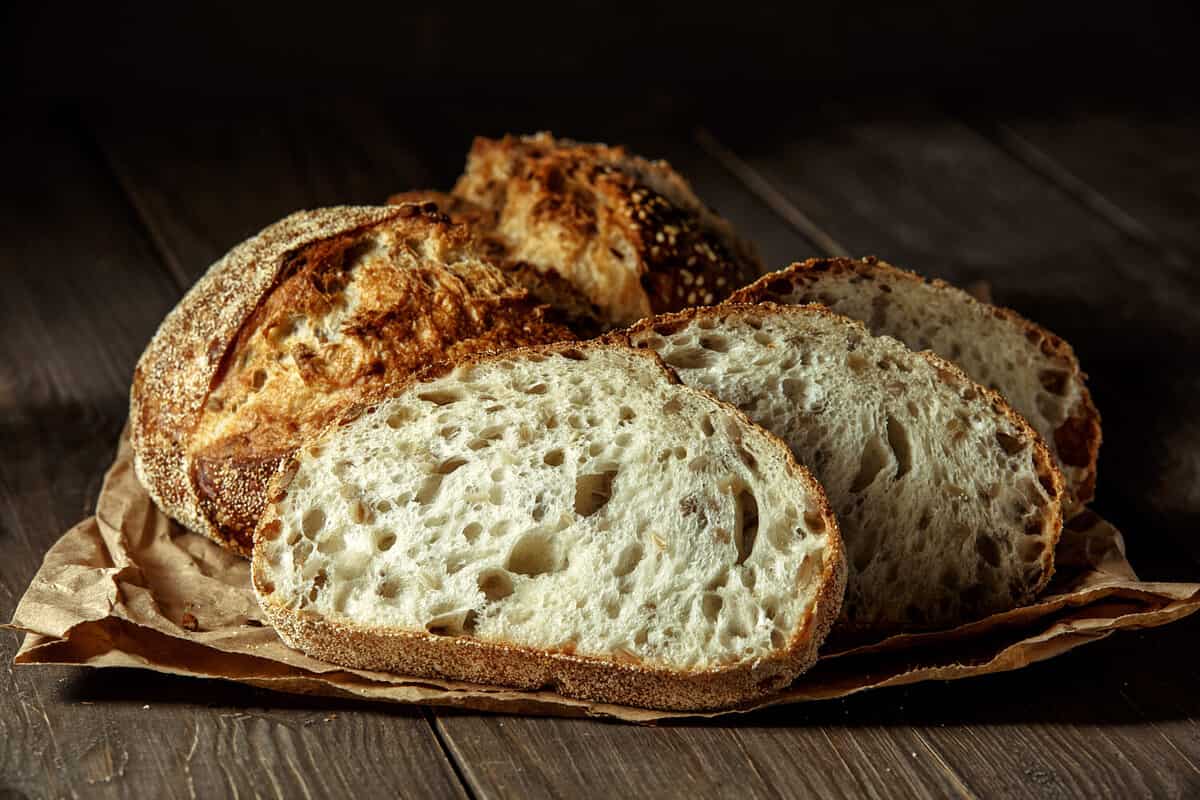 Bread, traditional sourdough bread cut into slices on a rustic wooden background. Concept of traditional leavened bread baking methods. Healthy food.