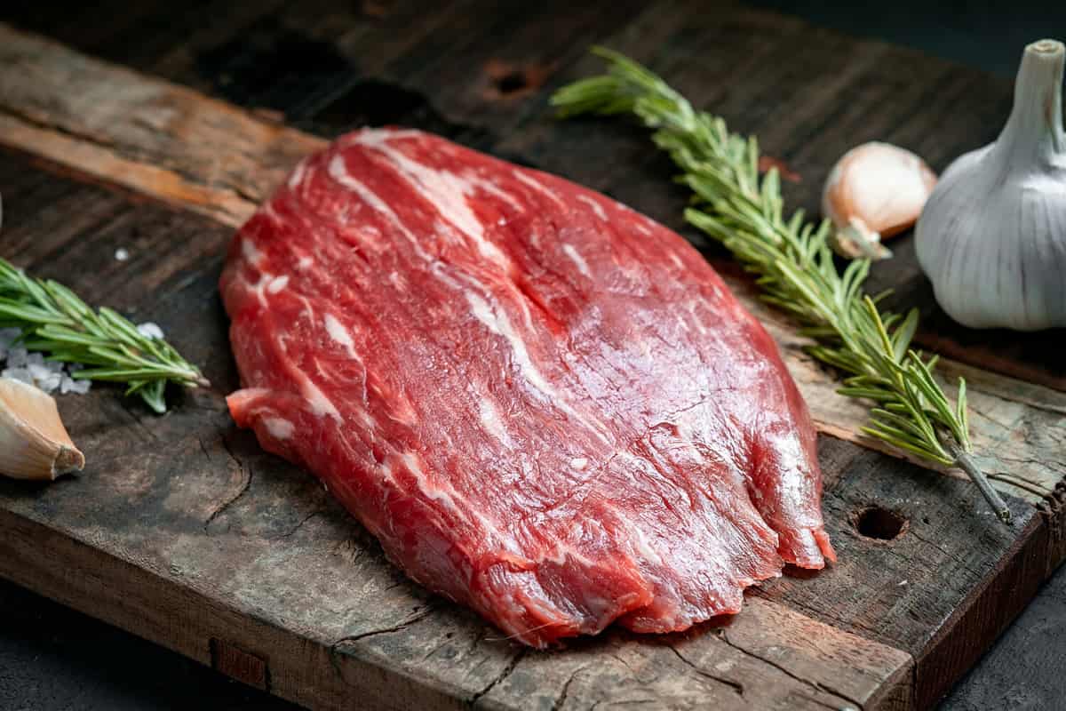 Raw flank beef steak and ingredients for cooking on a wooden Board, close up