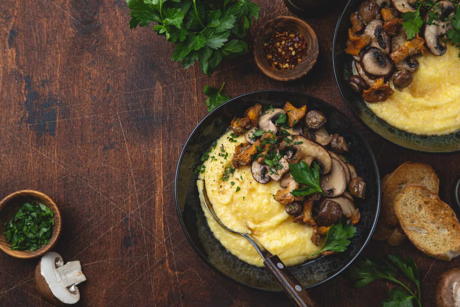 Creamy polenta with fried mushrooms, wooden background, top view, copy space