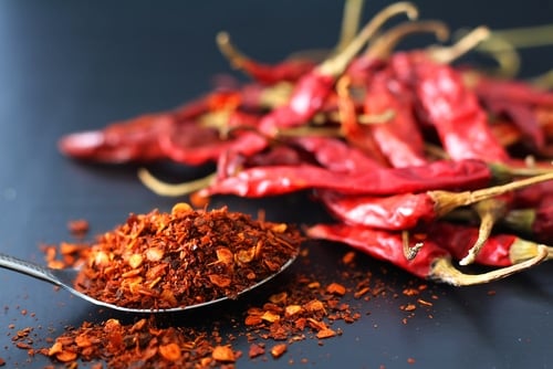 selective focus cayenne pepper on metal spoon and dried red chili on dark background.