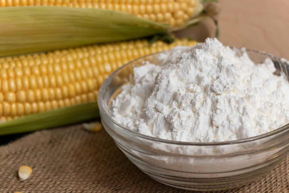 Swigs of raw corn on a burlap napkin and cornstarch in a glass dish.