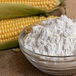 Swigs of raw corn on a burlap napkin and cornstarch in a glass dish.