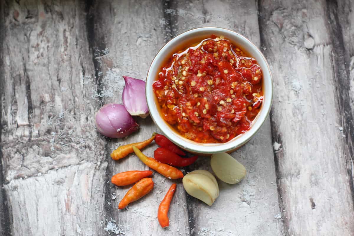 Sambal Bawang Or Spicy Onion Sauce with ingredients, Onion, Red Chilies, garlic, and salt.