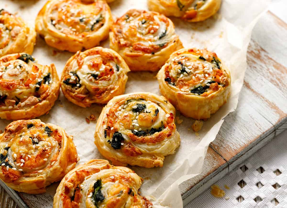 French Puff Pastry Pinwheels stuffed with salmon, cheese and spinach on on baking paper, close up view