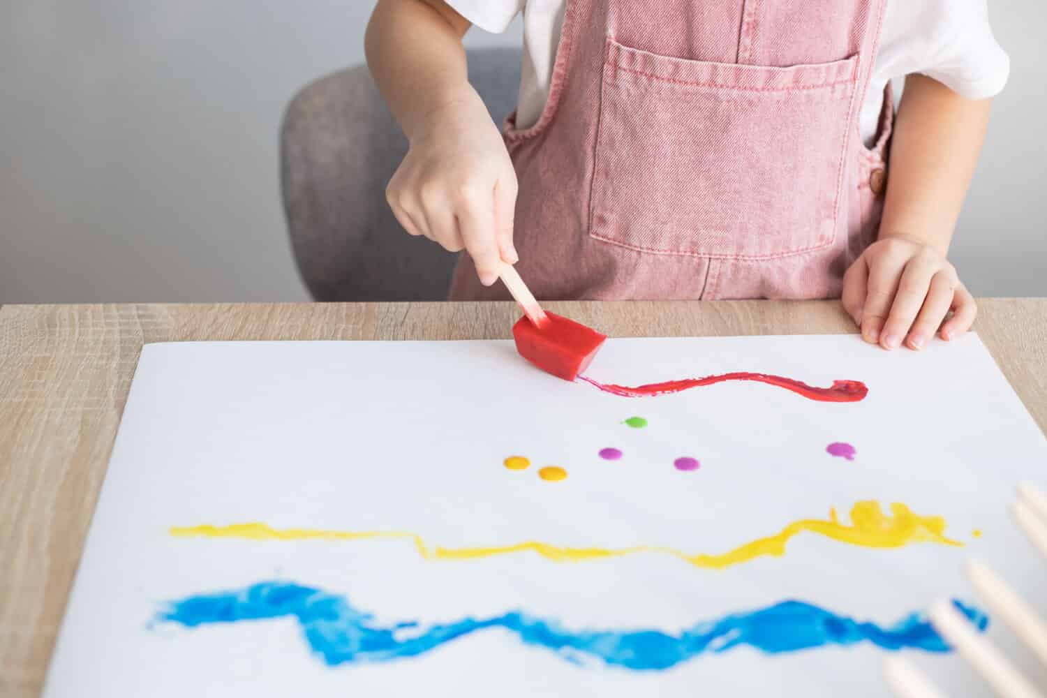 Child painting with colour ice cubes. Creative activities for toddlers. DIY, homemade paints.