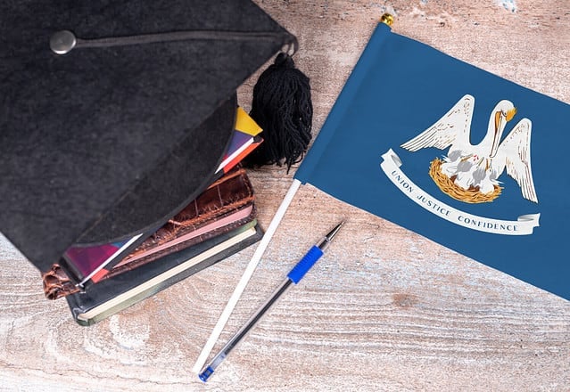 Black graduation hat on books next to Louisiana flag, education concept, top view