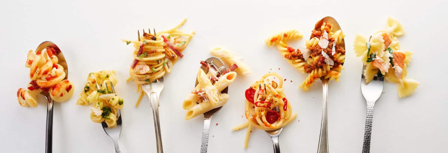 Various types of yummy pasta on spoons and forks (carbonara, spaghetti bolognese, pasta penne arrabiata, fusilli pasta bolognese)