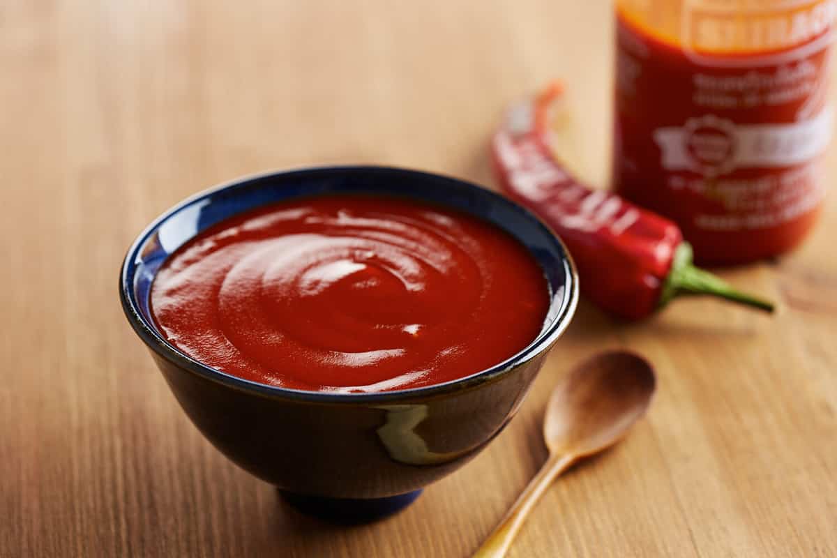 Bowl and bottle of sriracha sauce