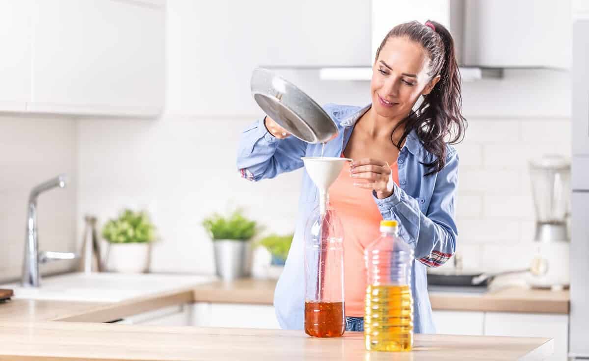 Woman pouring used cooking oil for recycling and reuse into the plastic bottle to be made in the factory into the fuel additive.