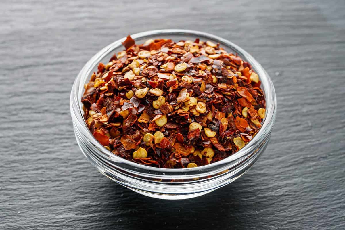 spicy chili flakes on a dark stone background.