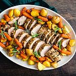 Roast Pork Tenderloin with Potatoes and Baby Carrots: Sliced pork medallions surrounded with vegetables on a platter