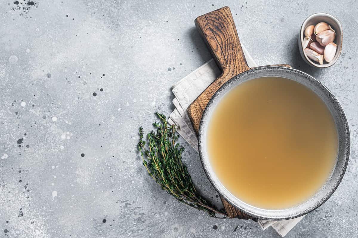 Bone meat chicken broth in a plate. Gray background. Top view. Copy space.