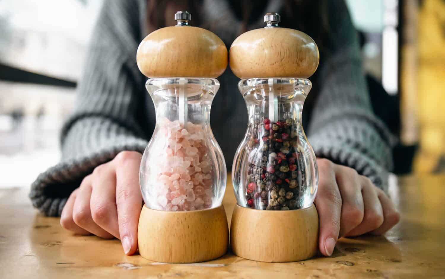 Close up of bottles of pink salt and pepper in containers with grinder prepared.