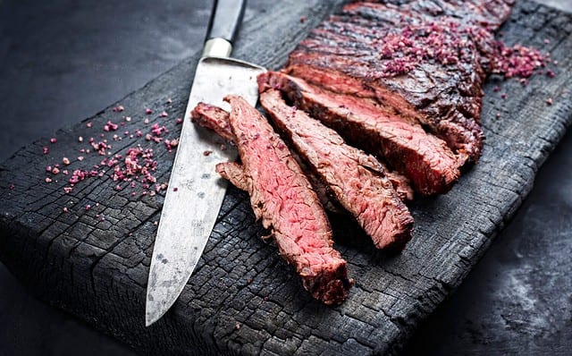 Barbecue wagyu bavette beef steak with red wine salt offered as close-up on charred wooden black board