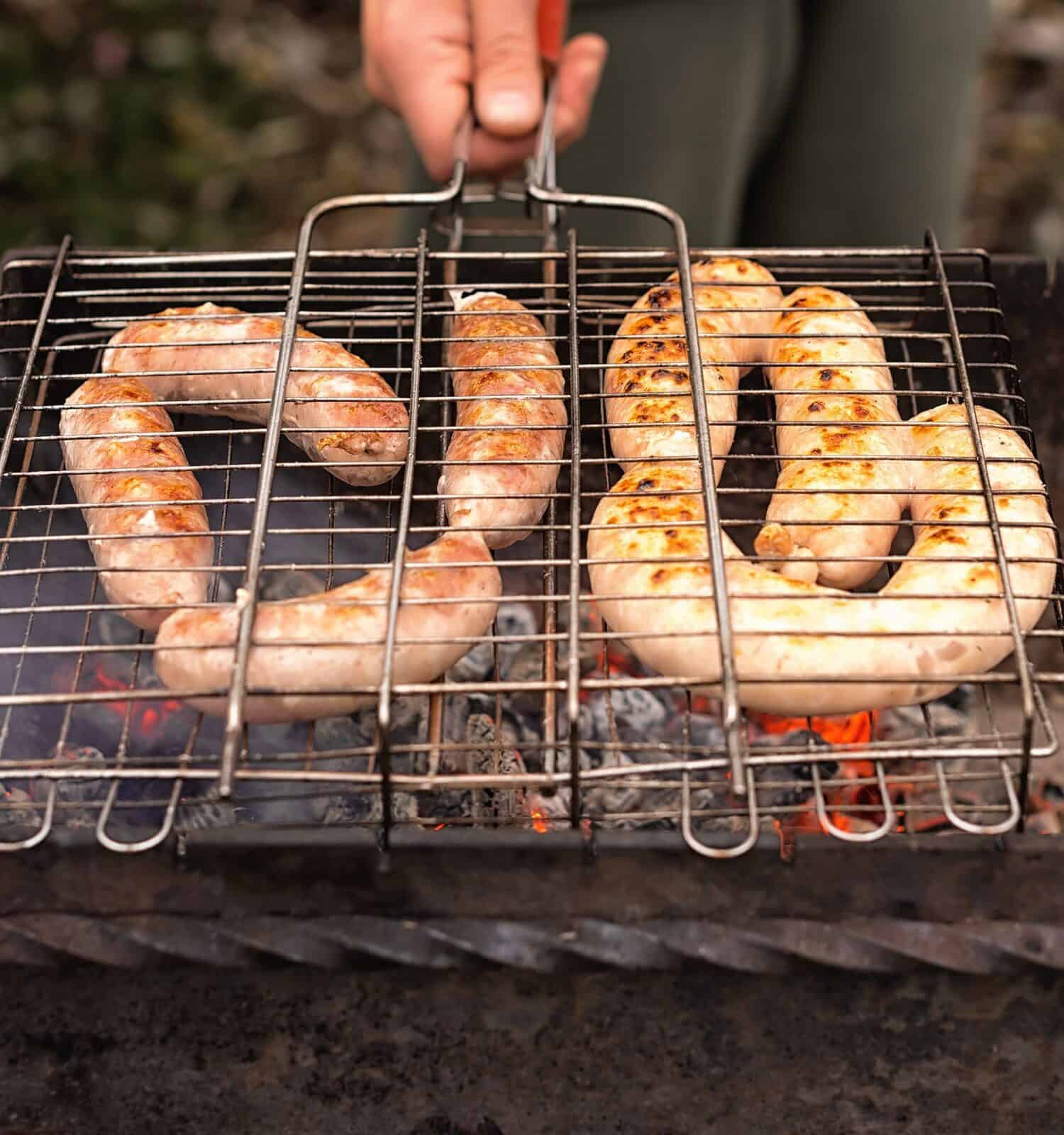 Pork and chicken sausages on the grill. Barbecue picnic in nature.