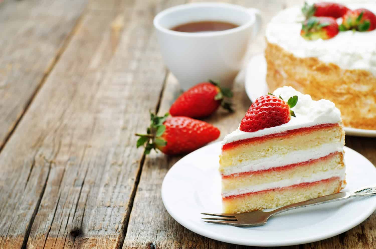 cake made with cake flour with cream and strawberries on a dark wood background. tinting. selective focus