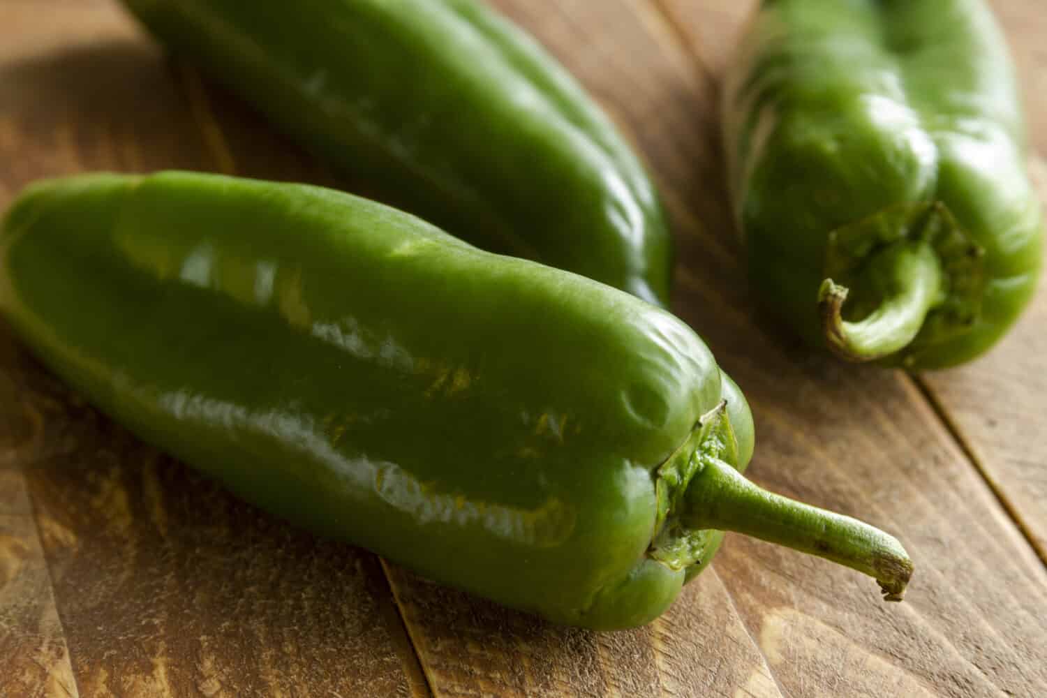 Close up of anaheim peppers sitting on wooden table