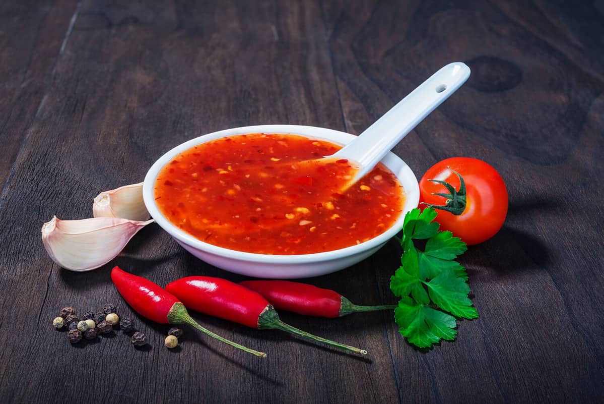 red hot sweet chilli sauce over old wooden background
