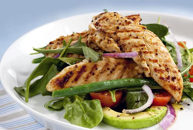 Salad of grilled chicken tenderloins with avocado, tomatoes, red onion, green beans, spinach and arugula. Delicious healthy eating.