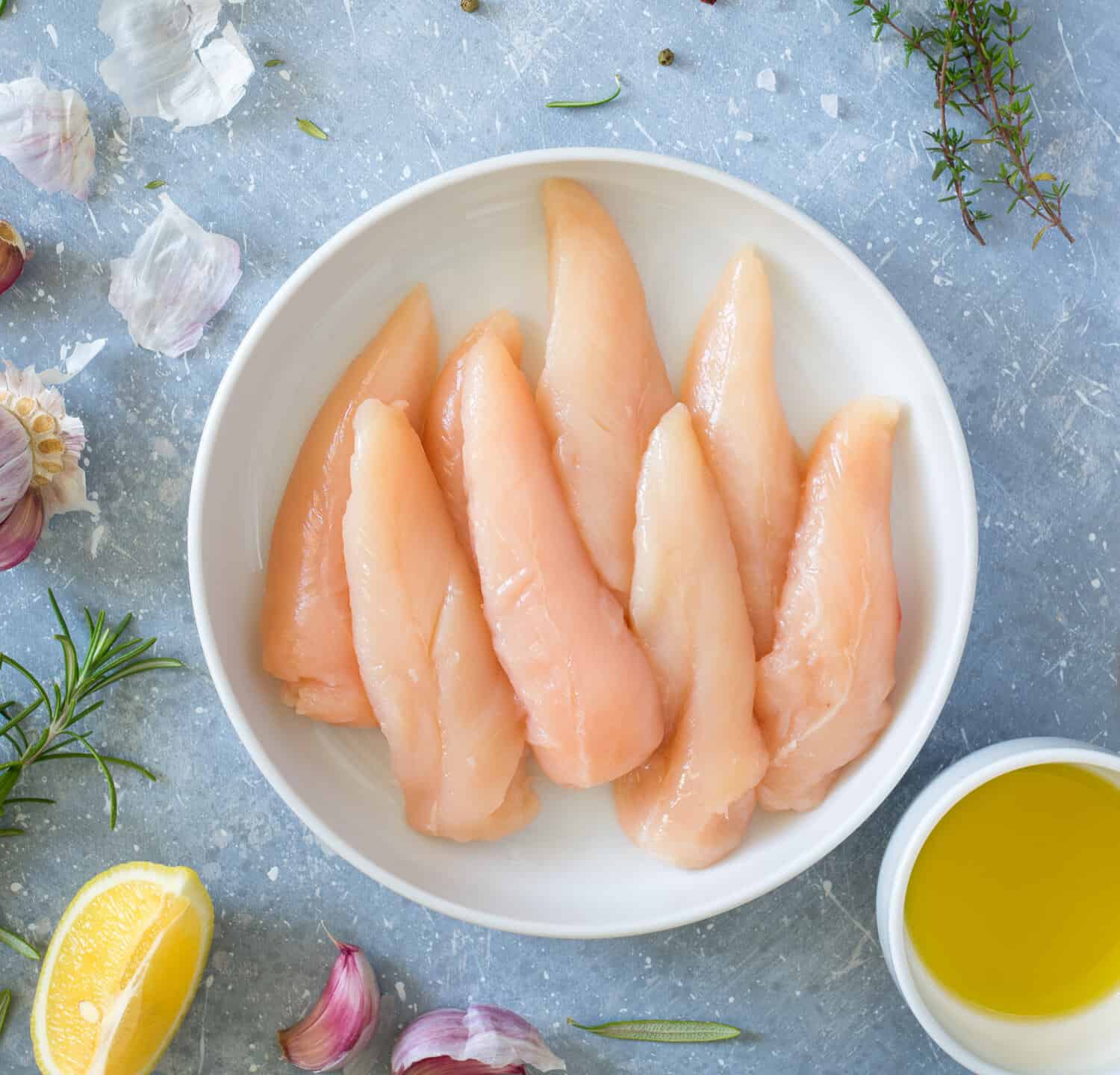 Fresh raw chicken tenders, lemon, garlic, rosemary, olive oil, pepper and salt