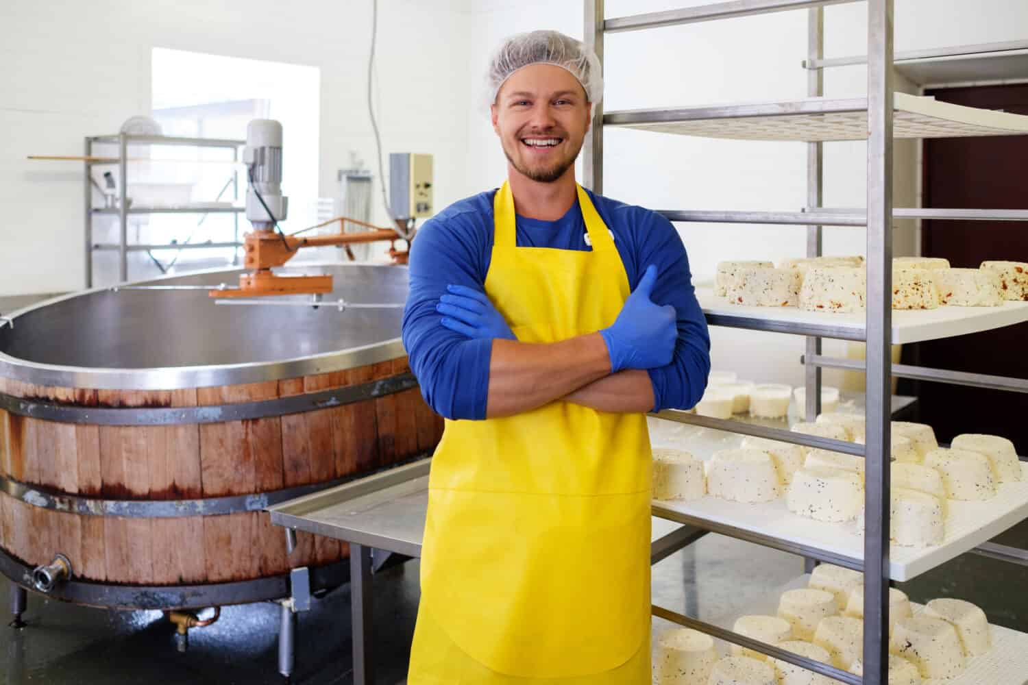 Handsome cheesemaker making curd cheese in his factory.