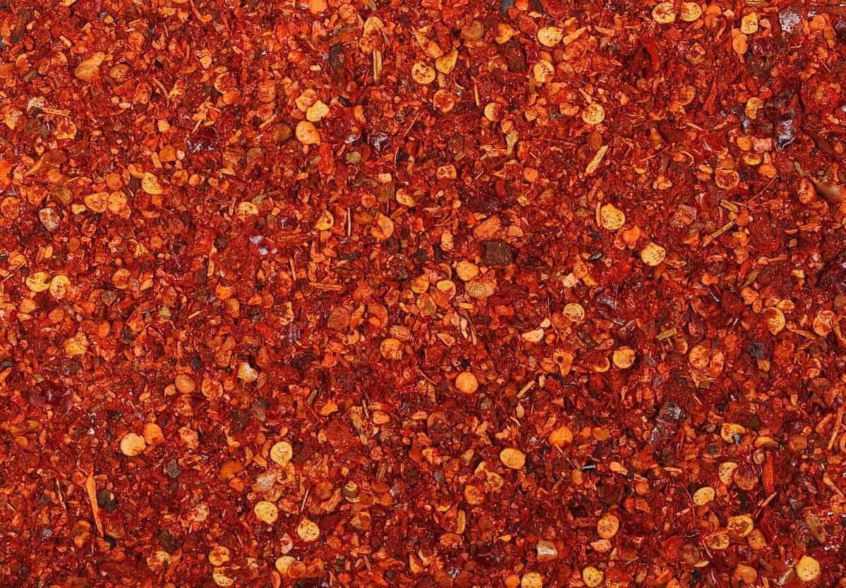 pile crushed red cayenne pepper, dried chili flakes and seeds isolated on white background