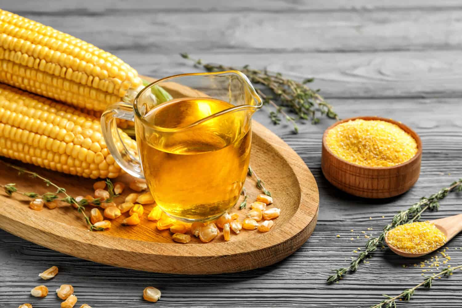 Composition with corn oil, kernels and flour on wooden background