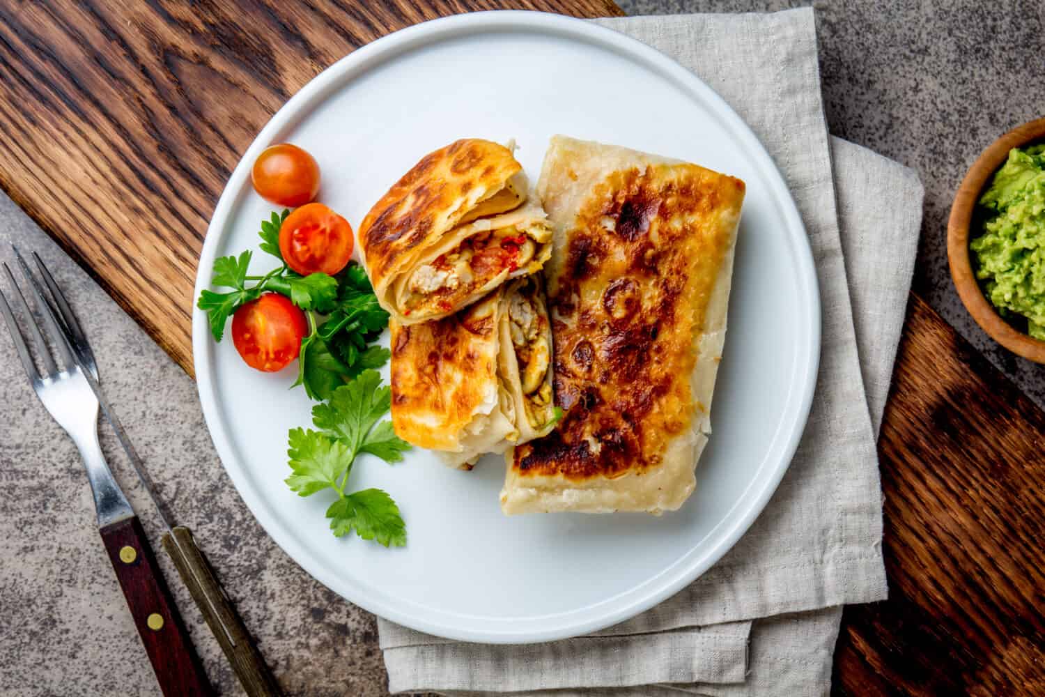 Mexican chimichanga on white plate served with guacamole sauce. Fried tortilla stuffed with chicken and vegetables. Traditional Mexican food, Top view.