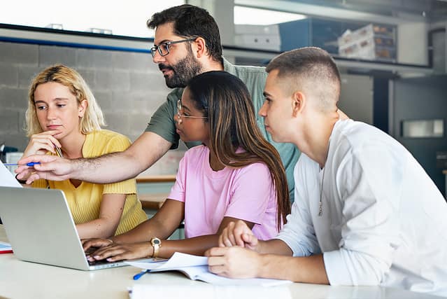 Young teacher helping teenager students at College, learning technology and science in preparatory course for university