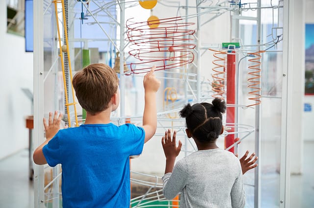 Two kids looking at a science exhibit, back view