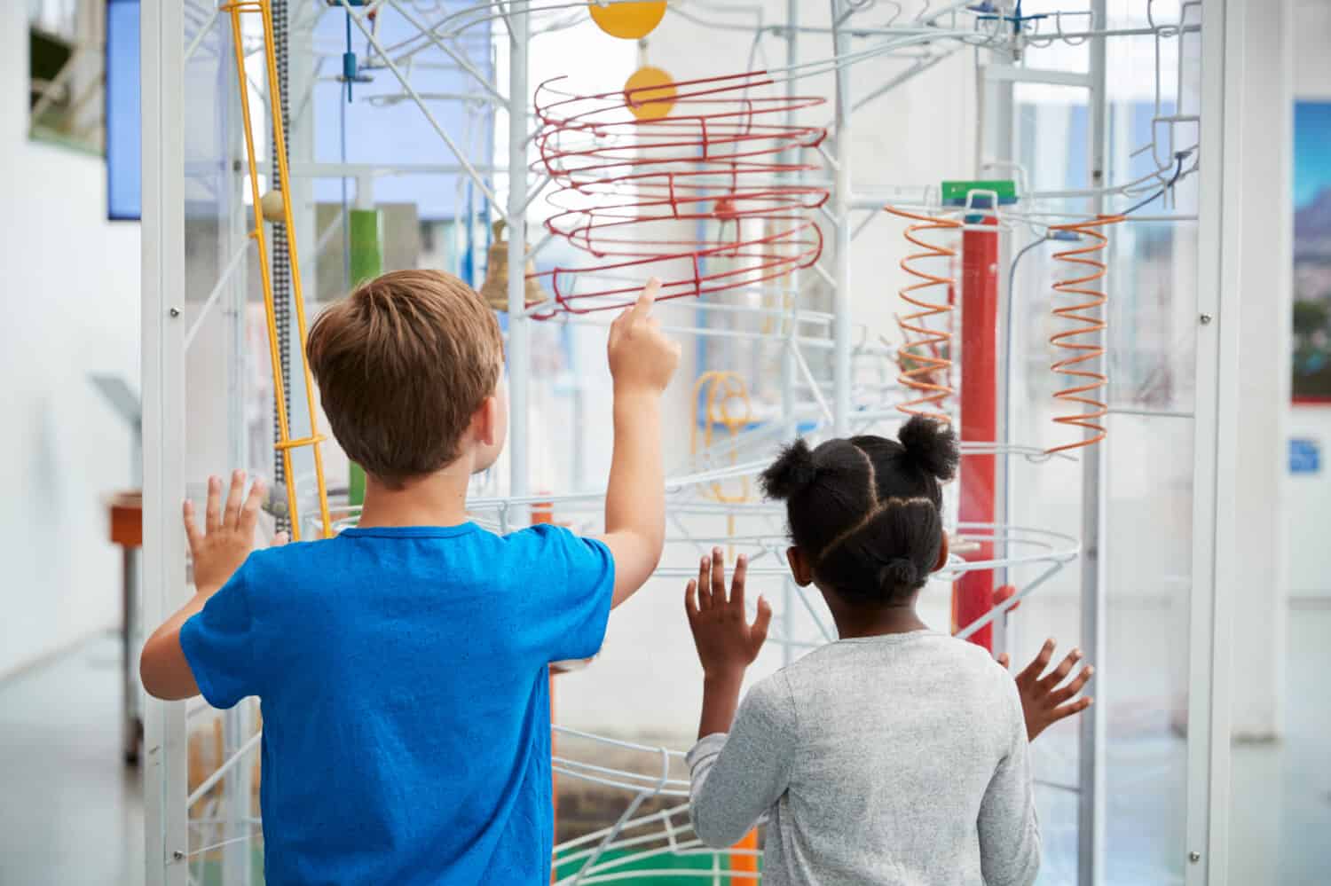 Two kids looking at a science exhibit,  back view