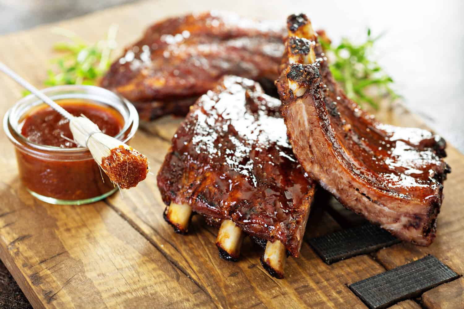 Grilled and smoked ribs with barbeque sauce on a carving board