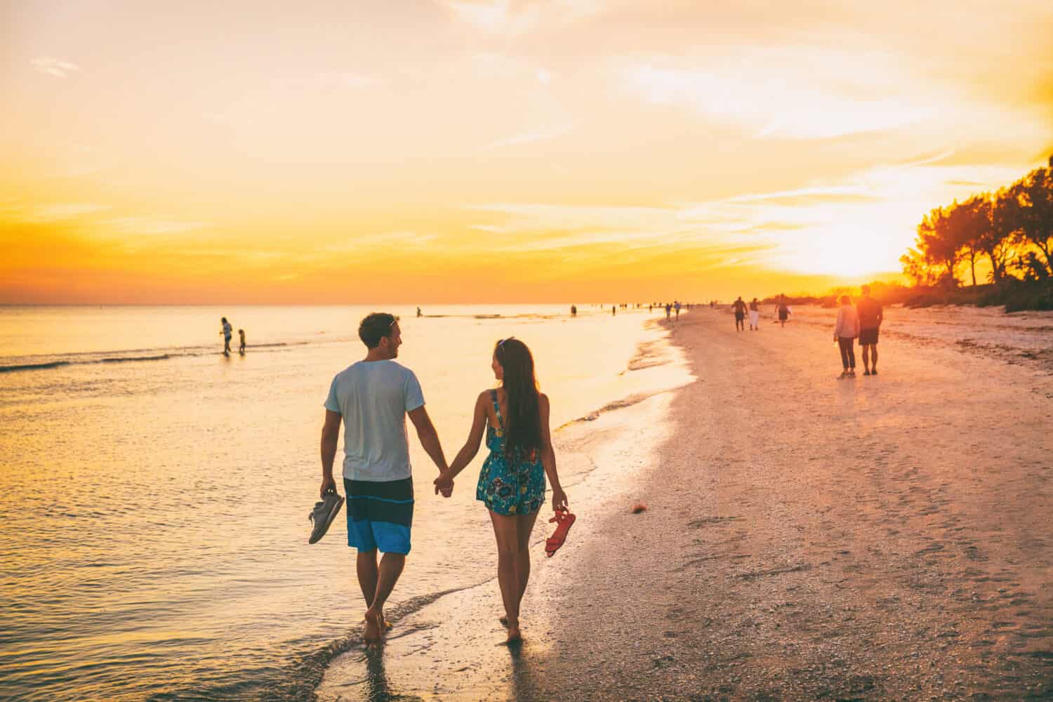 Beach summer beach people lifestyle happy couple enjoying sunset walk on Shelling beach famous tourist destination on the southwest coast of Florida -Gulf of Mexico. Sanibel Island, Florida.