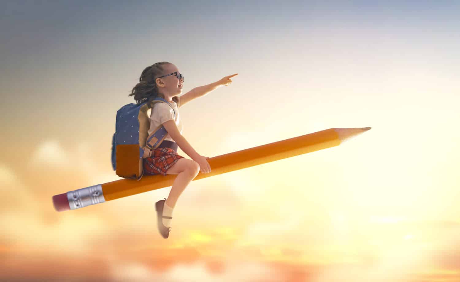 Back to school! Happy cute industrious child flying on the pencil on background of sunset sky. Concept of education and reading. The development of the imagination.