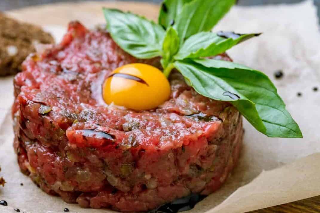 Tartare from beef with egg on wooden background