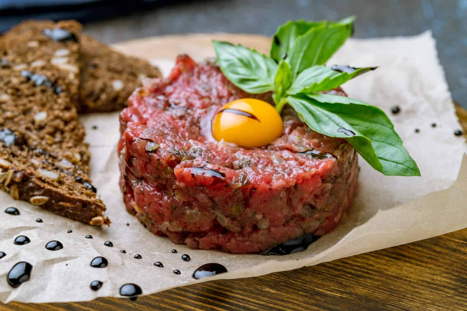 Tartare from beef with egg on wooden background