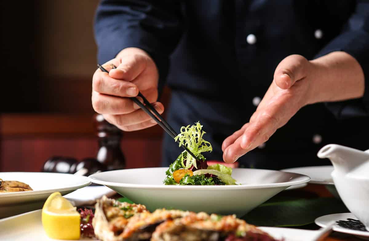 a hotel chef. He is decorating his food.