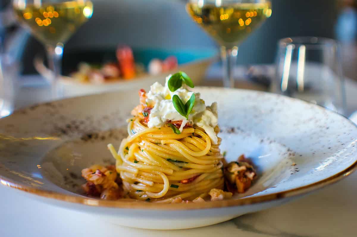 haute cuisine dish with spaghetti with lobster, buffalo stracciatella and a fine white wine. In a luxurious Italian restaurant