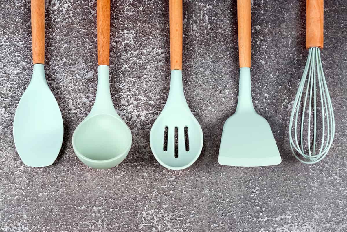 Kitchen utensils, home kitchen tools, mint rubber accessories on dark background. Restaurant, cooking, culinary, kitchen theme. Silicone spatulas and brushes, free copyspace for text
