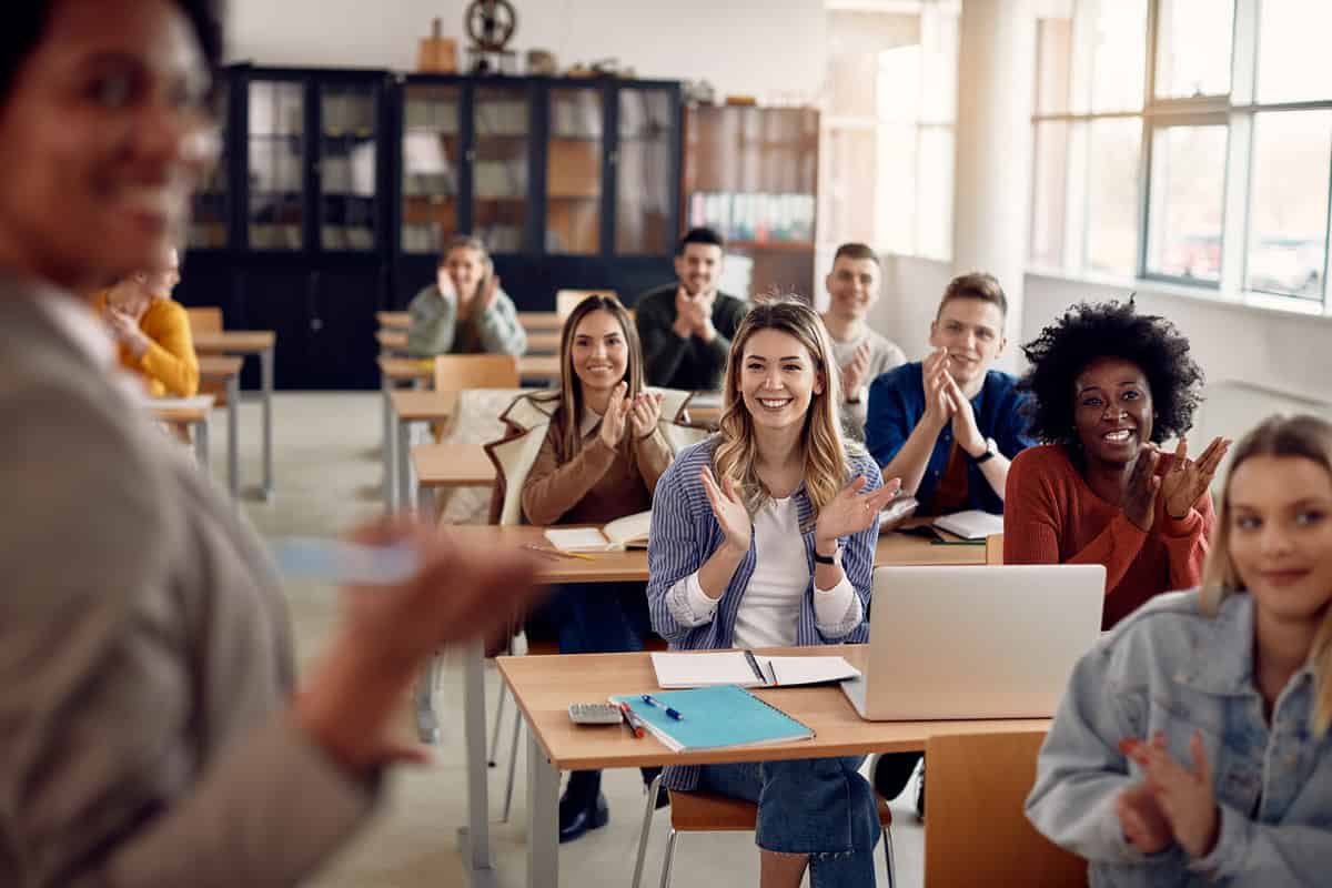 Group of happy students applauding to their lecturer while attending class at the university classroom.