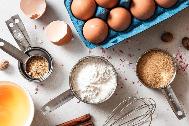 Baking ingredients and kitchen utensils on a white background top view. Baking background. Flour, eggs, sugar, spices, and a whisk on the kitchen table. Flat lay.