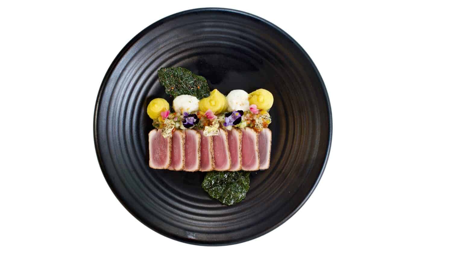 Top view of Tuna tataki on black plate, Isolated on white background. Japanese food.