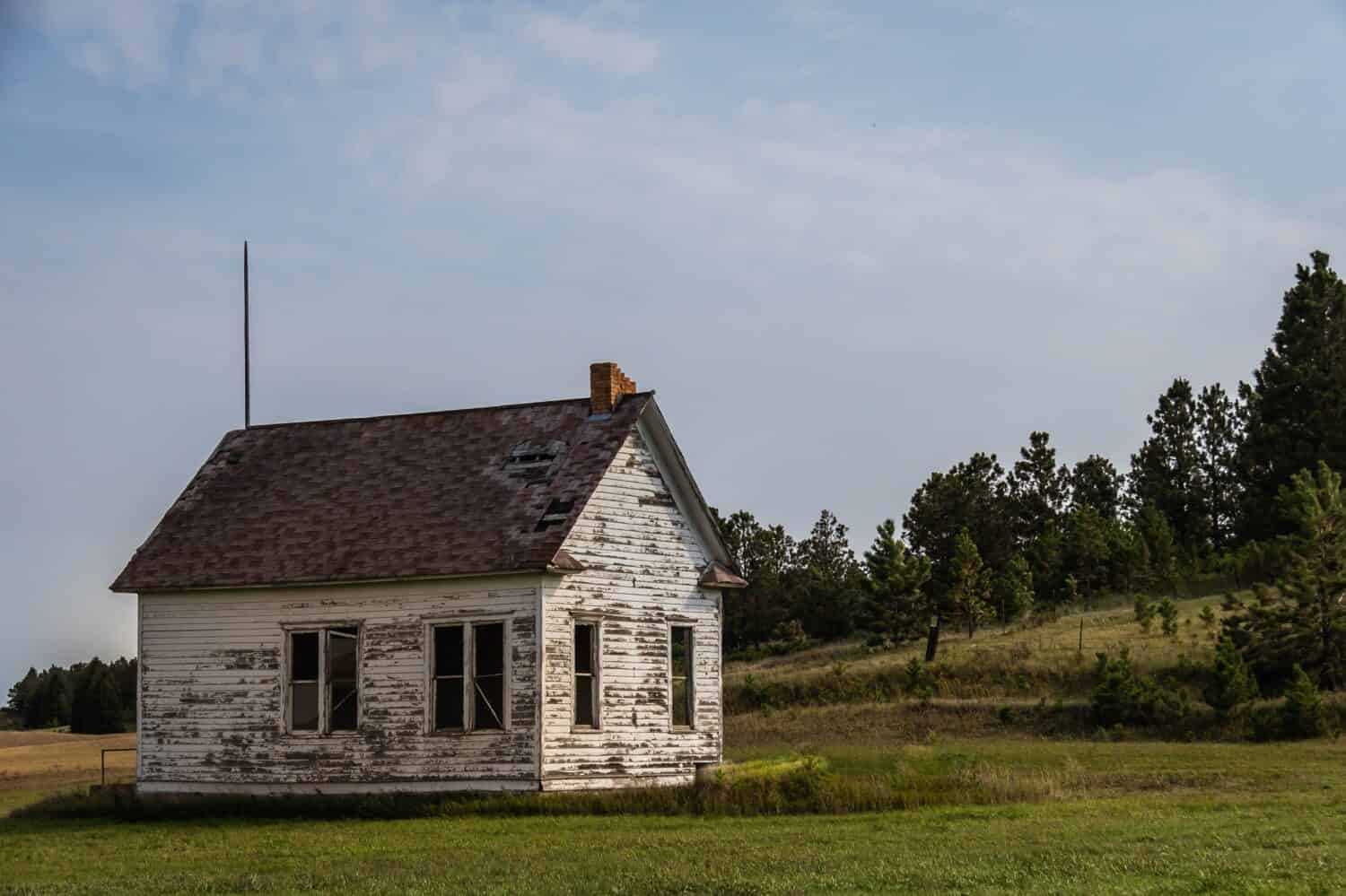 An old abandoned one room school house on the prairie of North Dakota in the evening.