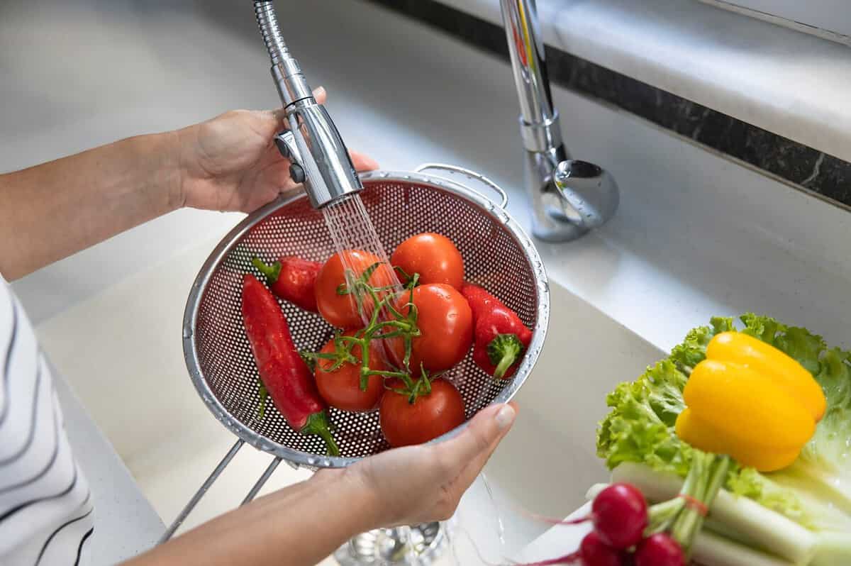 Woman washing vegetables on kitchen counter. Healthy foods