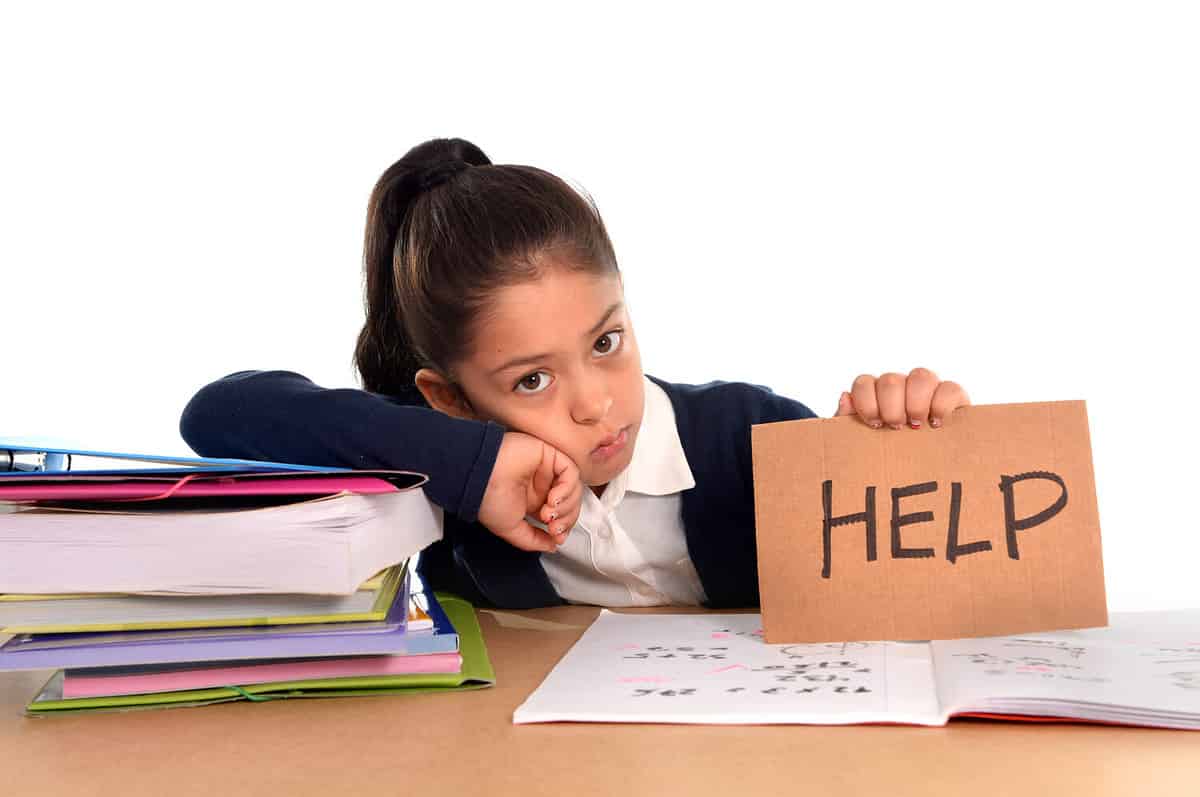 sweet little female latin child studying on desk asking for help in stress with a tired face expression in children education and back to school concept isolated on white background